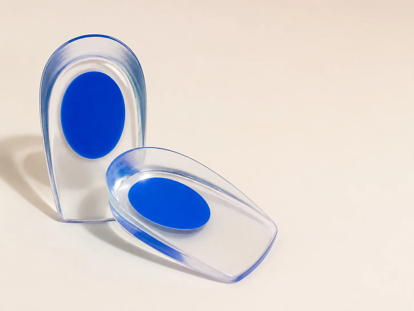 A pair of clear HeelSaver heel cushions with blue center pads on a cream surface